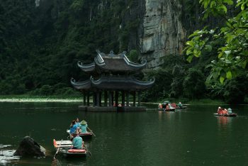 pexels-photo-28949259-28949259 Traditional boats navigate the serene waters of Ninh Bình with lush karst landscape backdrop.